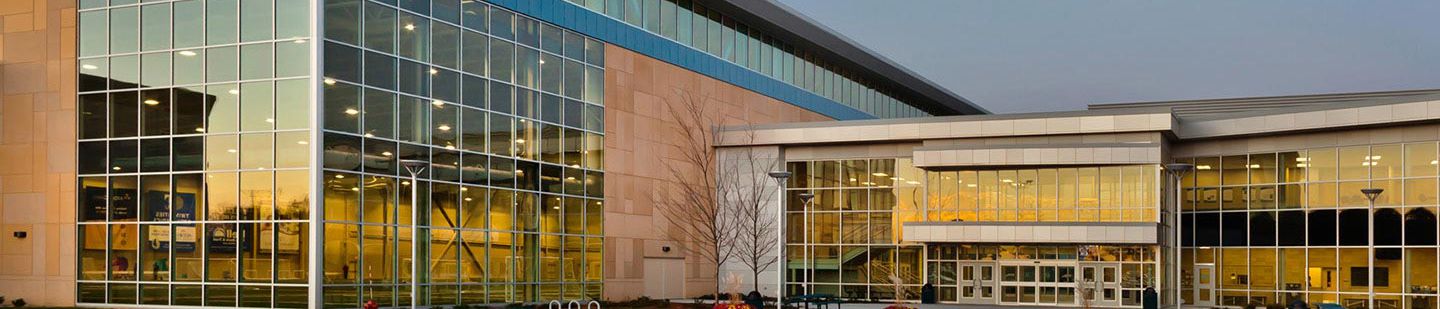 Wide view of Bielenberg Sports Center from the front, picturing the entrance at sunset