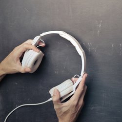 Image of hands holding headphones against a concrete background