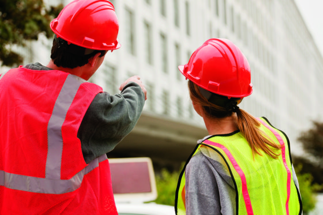 Workers in safety vests and helmets using analyzing operational efficiency of structure