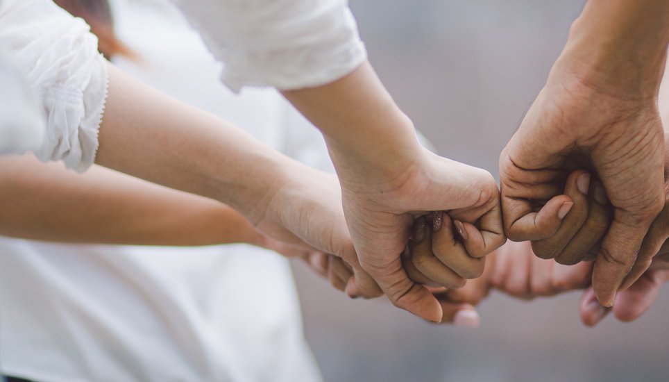 Multiple people all putting their hands together in a show of solidarity