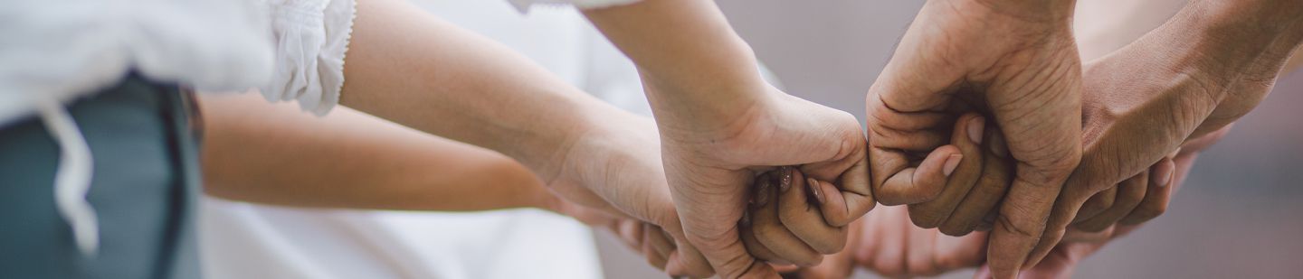 Multiple people all putting their hands together in a show of solidarity