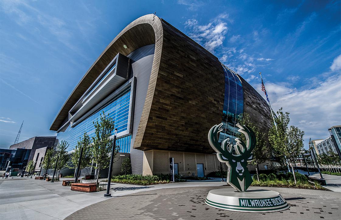 Exterior of Fiserv Forum with bucks logo monument in front and blue sky