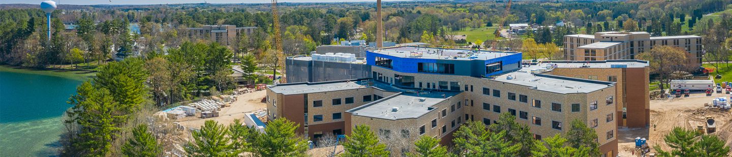 Wide aerial view of John R Moses Skilled Nursing Facility surrounded by trees and a lake