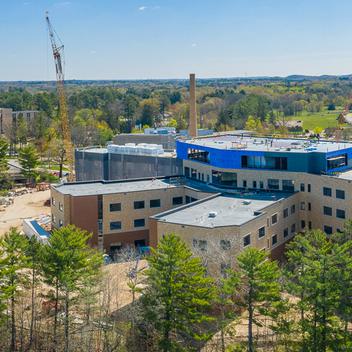 Wide aerial view of John R Moses Skilled Nursing Facility surrounded by trees and a lake