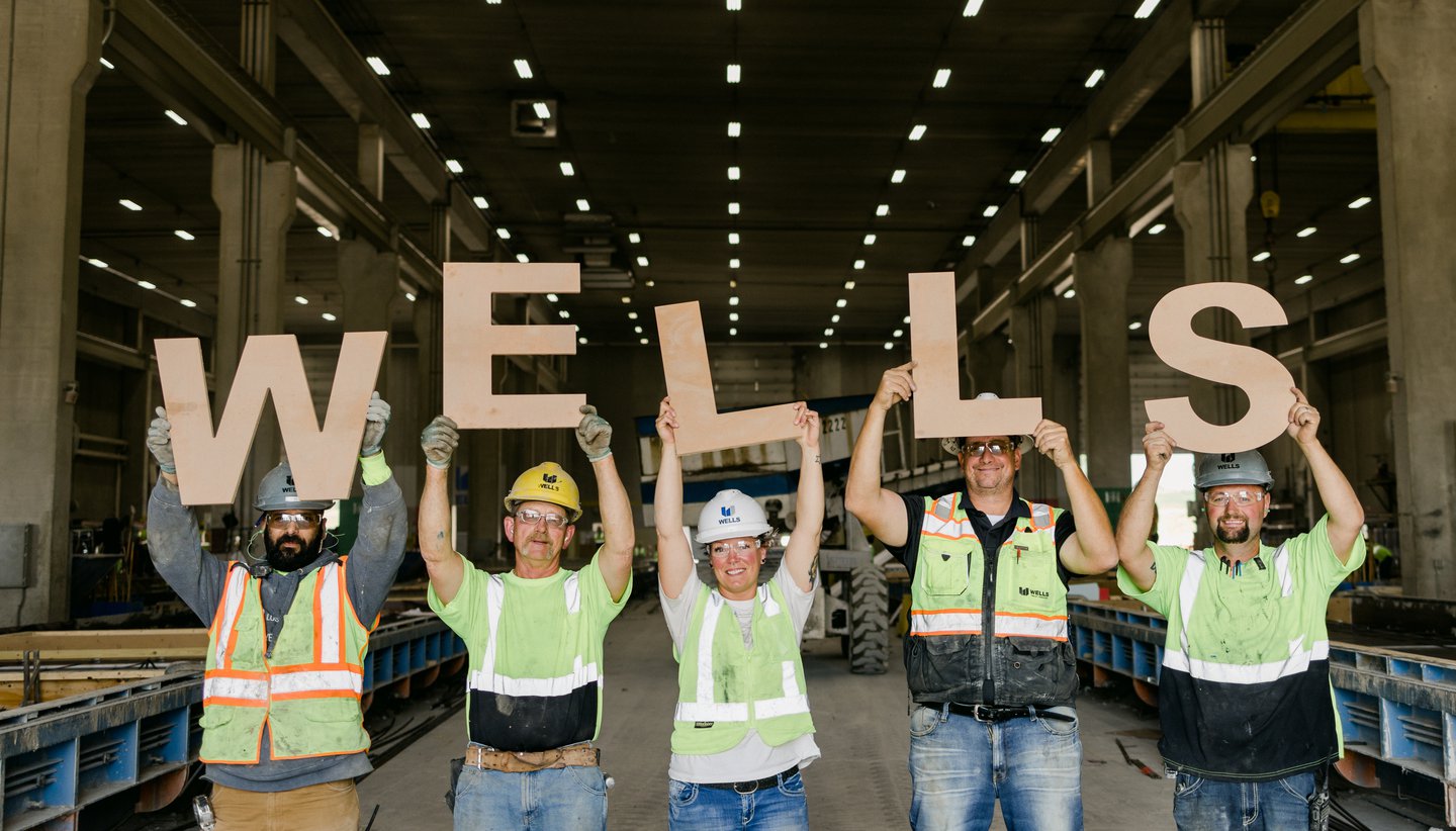 employees holding up letters to spell out WELLS