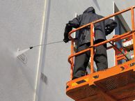 worker applying spray to building