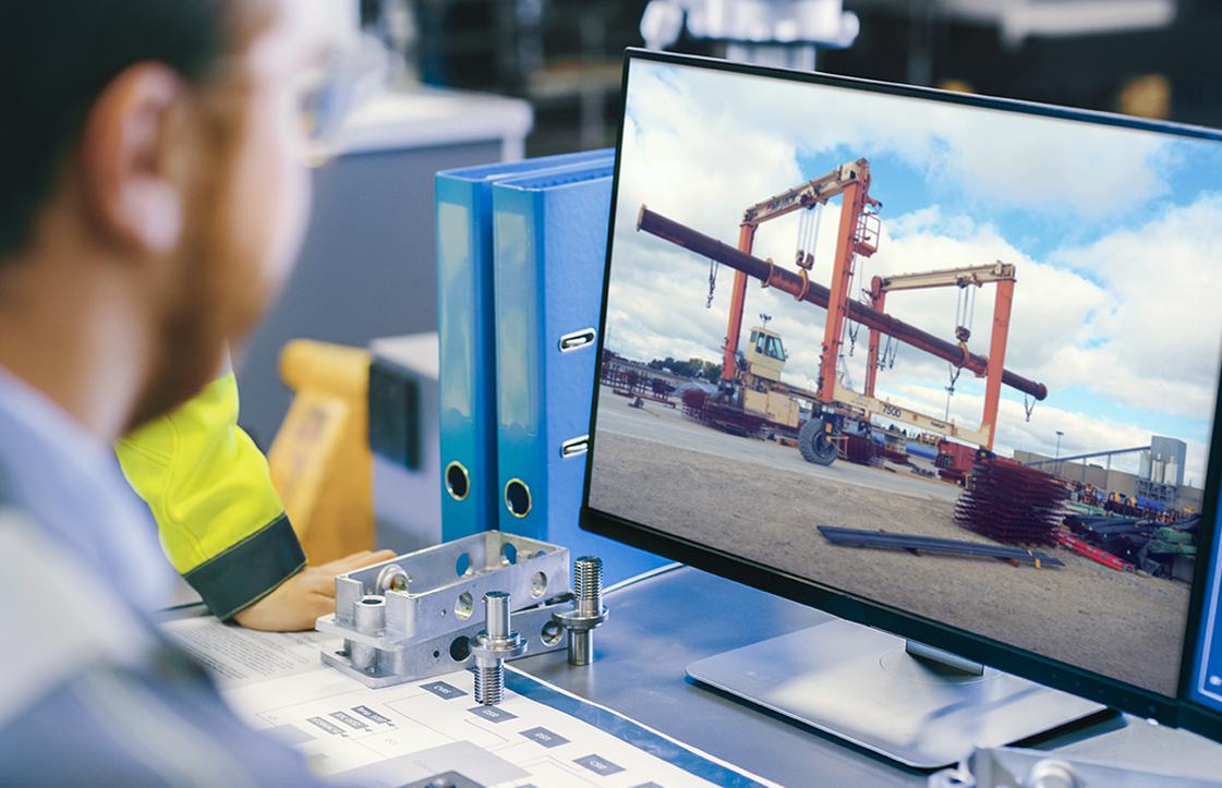 Man looking at computer with blue sky and crane