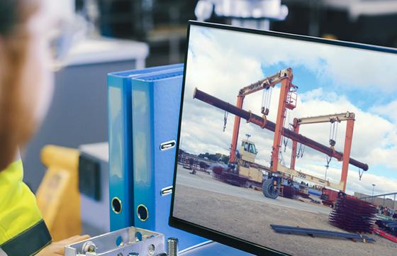 Man looking at computer with blue sky and crane