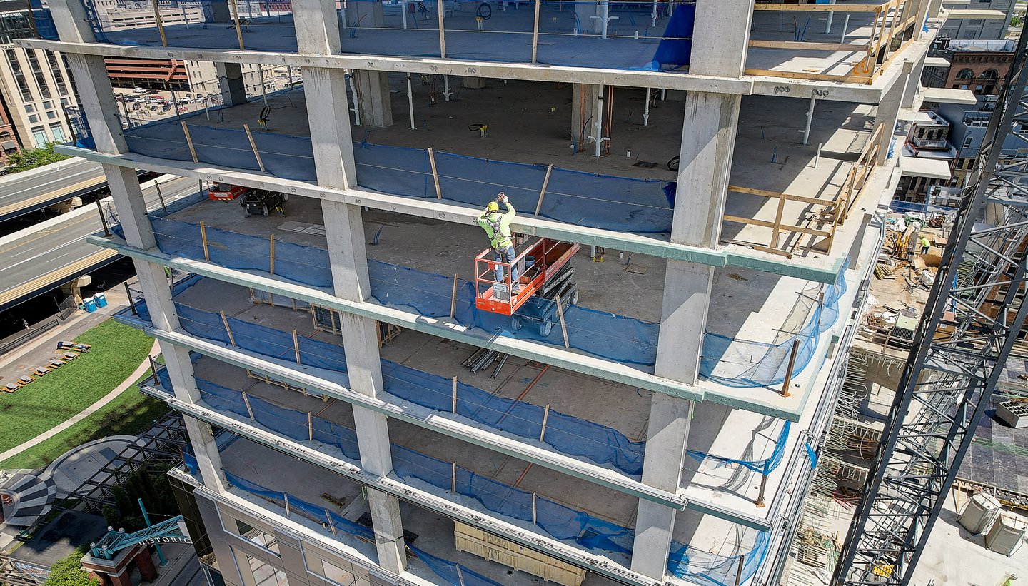 worker applying liquid air barrier on each floor of building in construction