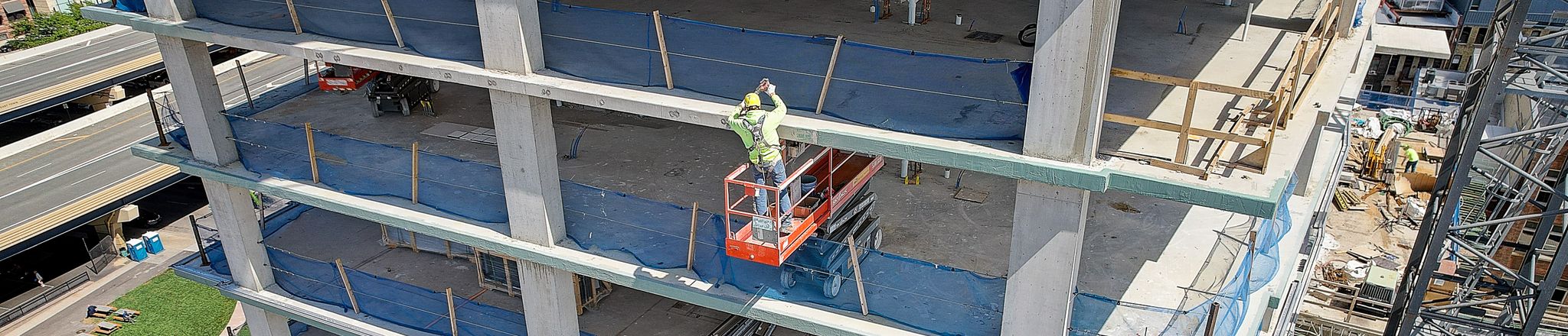 worker applying liquid air barrier on each floor of building in construction