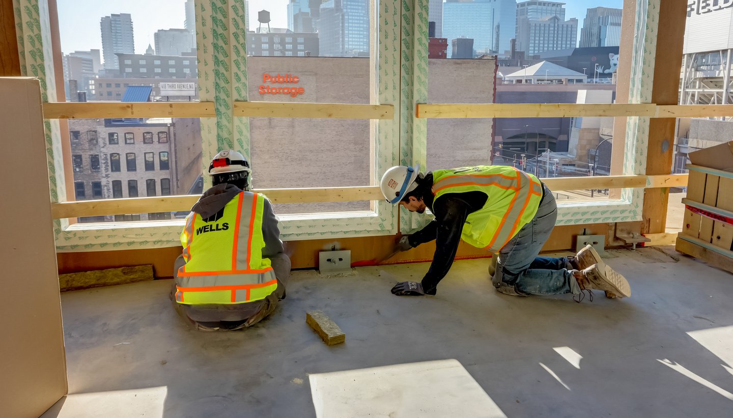 workers applying firestopping caulk between floors