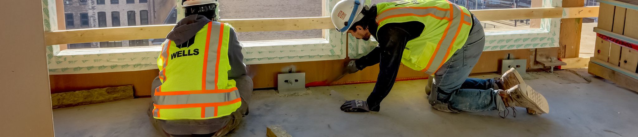 workers applying firestopping caulk between floors