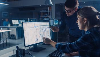 two engineers pointing at floor plans on a computer screen