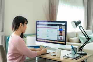 Woman videoconferencing in front of her computer at home
